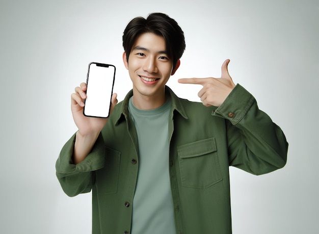 Asiatischer Mann mit grünem Hemd, der mit einem Smartphone auf das Telefon zeigt, lächelt, Online-Shopping-Konzept