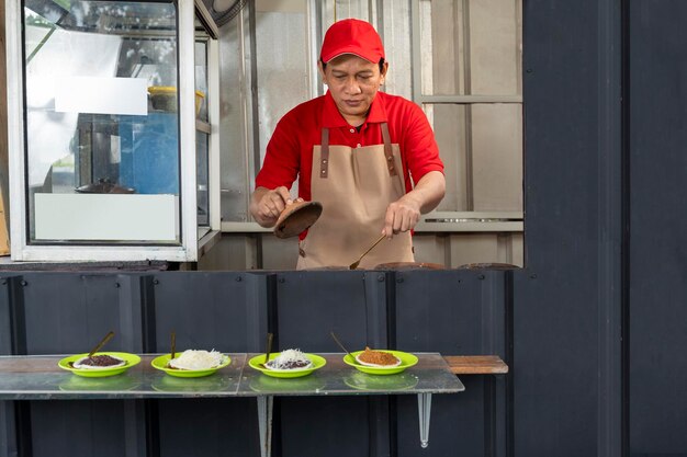 Asiatischer Mann mit Hut und Schürze, der Serabi kocht