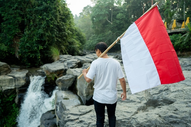 Asiatischer Mann mit indonesischer Flagge von Indonesien oben auf dem Berg