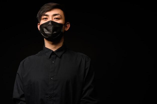 Asiatischer Mann mit medizinischer Gesichtsmaske zum Schutz des Coronavirus. Junger asiatischer Mann, der in der Stadt mit verschmutzter Luft lebt.