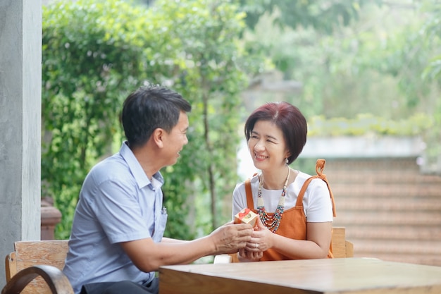 Asiatischer Mann mittleren Alters schenkt seiner Frau am Hochzeitstag ein Jubiläum