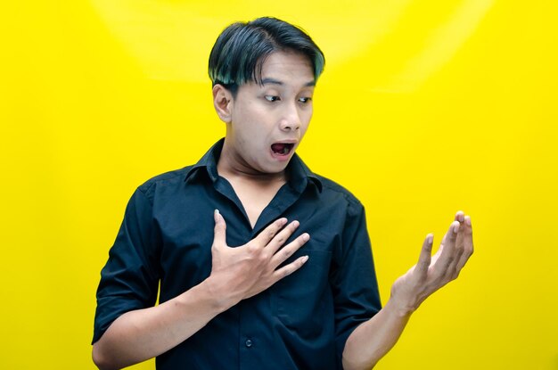 asiatischer Mann sieht überrascht aus, öffnet seinen Mund und zeigt auf die Gegenwart und wirbt mit seinem Finger