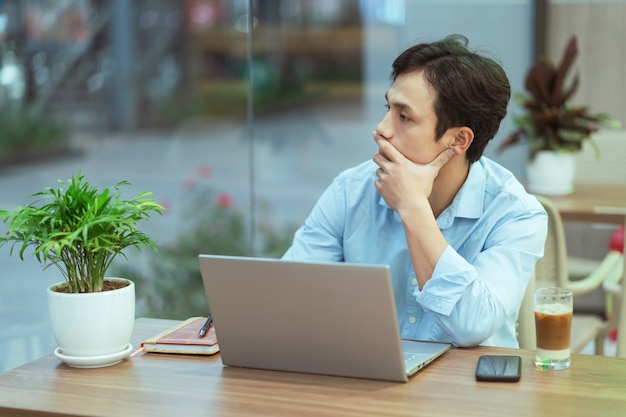 Asiatischer mann sitzt allein arbeitend an einem kaffeegeschäft