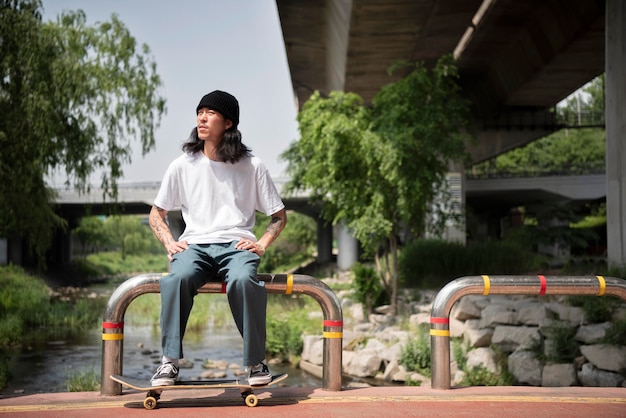 Foto asiatischer mann sitzt nach dem skateboarden eine weile