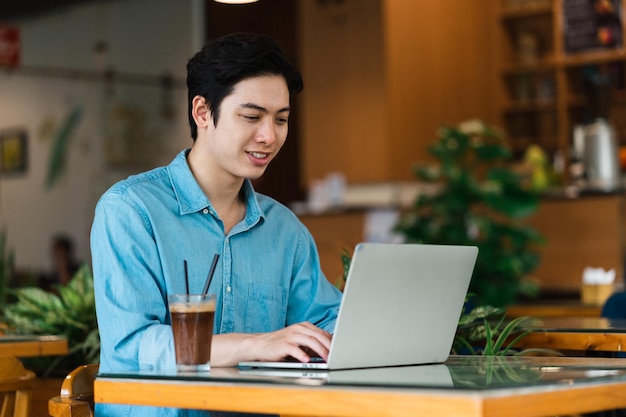 Asiatischer Mann sitzt und trinkt Kaffee