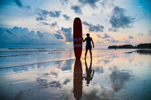 Asiatischer Mann tragen Surfbrett am Strand