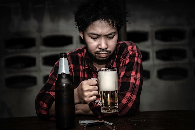 Asiatischer Mann trinkt Wodka allein zu Hause in der NachtThailänderStress Mann betrunken Konzept