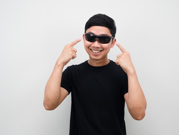 Asiatischer Mann zeigt fröhlich mit dem Finger auf die Sonnenbrille auf seinem Gesicht