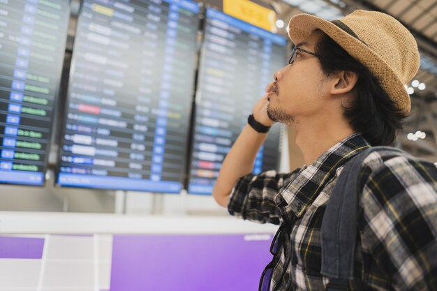 Asiatischer Manntaschen-Packtourist im Flughafen.