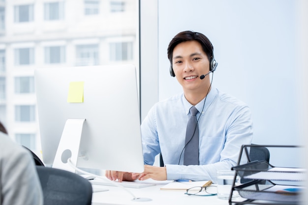 Asiatischer Manntelemarketer, der im Büro arbeitet