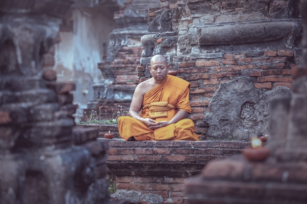 Asiatischer Mönch, der am Tempel meditiert