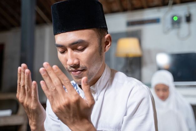 Asiatischer muslimischer Ehemann und Ehefrau beten zusammen zu Hause Jamaah