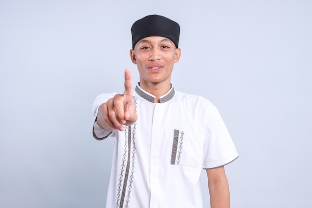 Asiatischer muslimischer junger Mann, der kein Zeichen mit dem Zeigefinger zeigt oder auf weißen Hintergrund nach oben zeigt