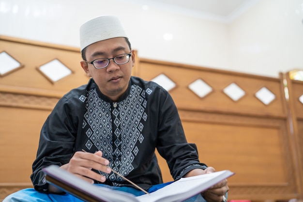 Asiatischer muslimischer Mann, der Koran liest