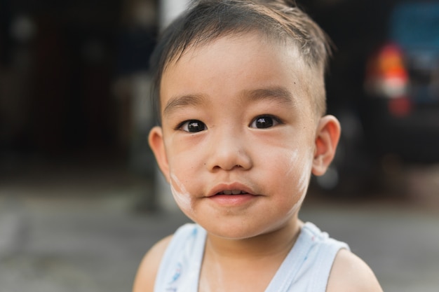 Foto asiatischer netter junge, der kamera lächelt und betrachtet. kinder porträt.
