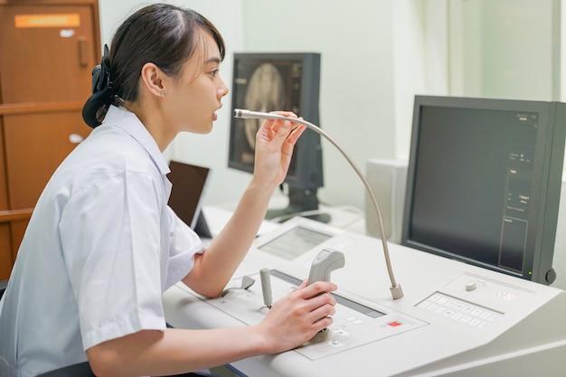 Foto asiatischer radiologe, der an der fluoroskopiekonsole arbeitet, medizinisches konzept