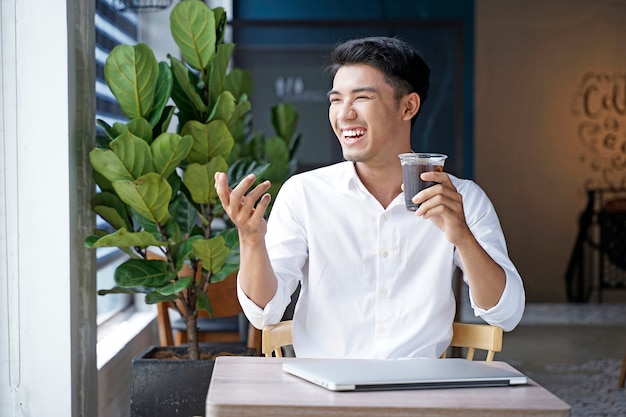 Asiatischer schöner Geschäftsmann oder Büroangestellter, der am Kaffeehaus arbeitet