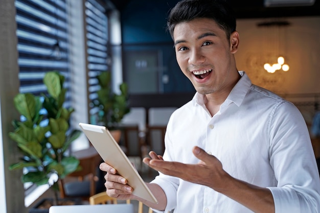 Asiatischer schöner Geschäftsmann oder junger Student, der Pad-Tablet-Computer verwendet