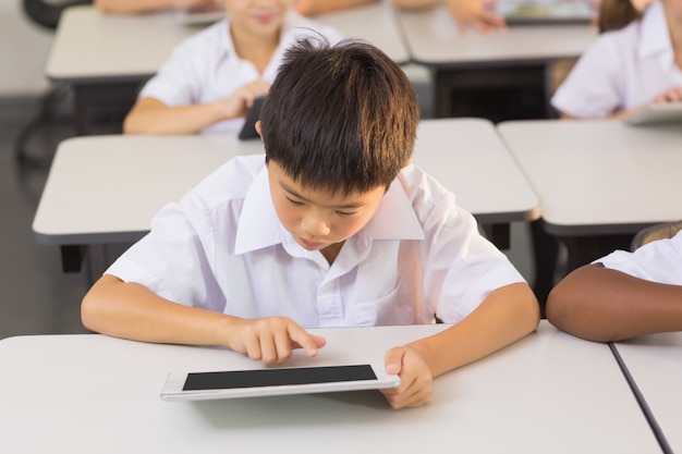 Asiatischer Schüler, der digitales Tablett im Klassenzimmer verwendet