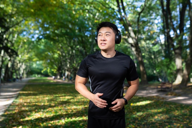Asiatischer Sportler läuft morgens mit Kopfhörern und hört Musik und Hörbücher mit Podcasts