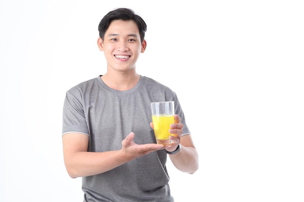 Asiatischer, sportlich gutaussehender und fröhlicher junger Mann mit einem Glas Vitamin-C-Orangensaft isoliert auf dem Hintergrund