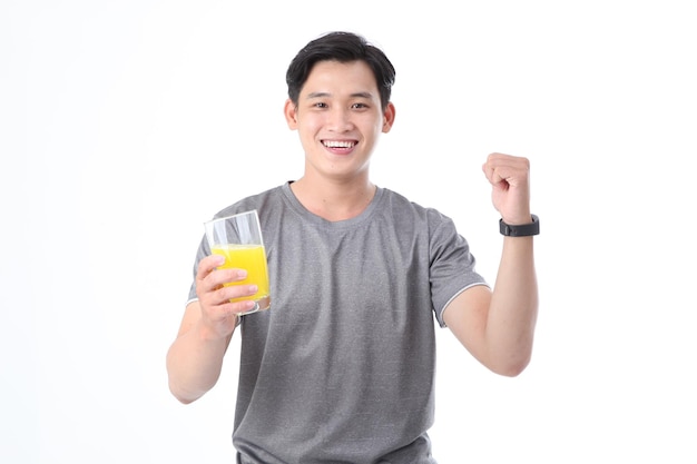 Asiatischer, sportlich gutaussehender und fröhlicher junger Mann mit einem Glas Vitamin-C-Orangensaft isoliert auf dem Hintergrund