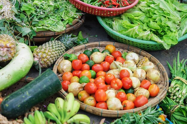 Asiatischer Straßenbauernmarkt, der frisches Obst und Gemüse in Hoi An, Vietnam verkauft. Tomaten, Limetten, Zwiebeln, Salat, Zucchini und Ananas. Grüne und rote Farben.