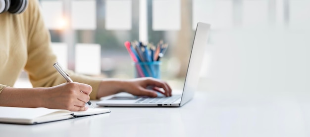 Asiatischer Student, der mit Laptop sitzt und online in der Bibliothek an der Universität studiert und Online-Online-Web-Bildungskonzept studiert