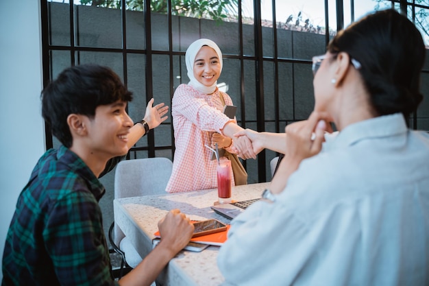 Asiatischer Student im Hijab schüttelt Mädchen beim Treffen die Hand