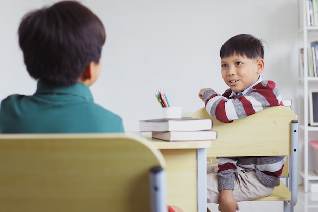 Asiatischer Student spricht mit seinem Freund in einem Klassenzimmer