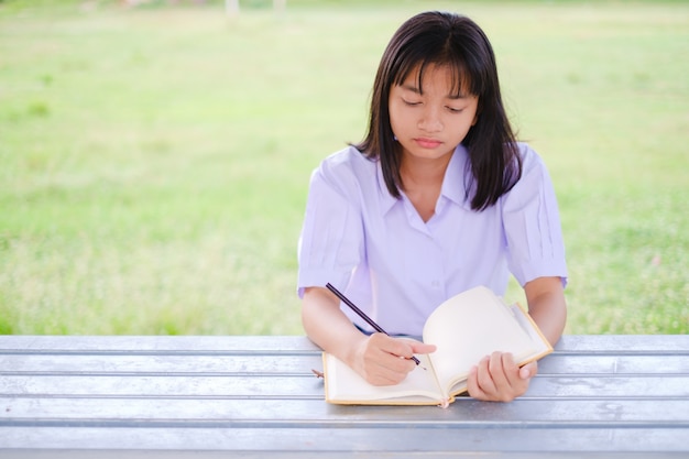 Asiatischer Student studiert draußen in der Schule.