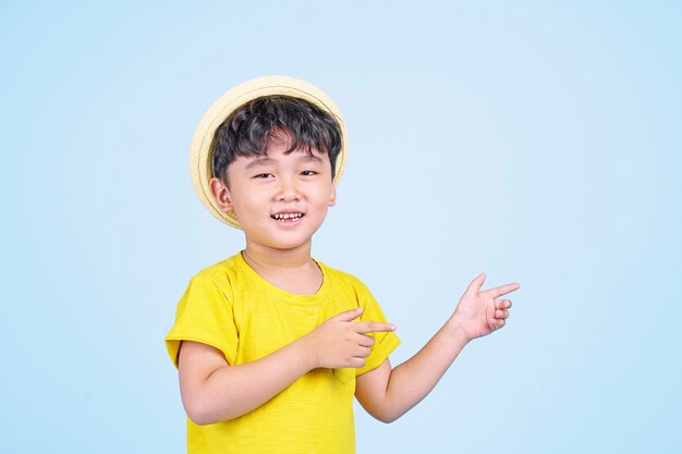 Asiatischer süßer kleiner Junge, der etwas mit seiner Hand auf farbigem Hintergrund präsentiert