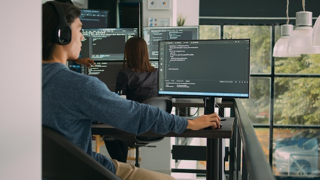 Asiatischer Systemingenieur, der mit HTML-Skript auf dem Computerbildschirm arbeitet und das Terminalfenster verwendet. Programmierschnittstelle für Softwareentwickler, die einen innovativen KI-Algorithmus in Büroräumen schreibt.