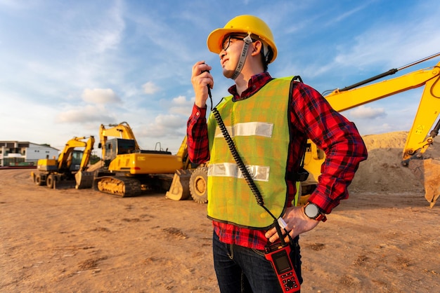 asiatischer techniker bauingenieur spricht mit team per walkie-talkie über baupläne auf der baustelle