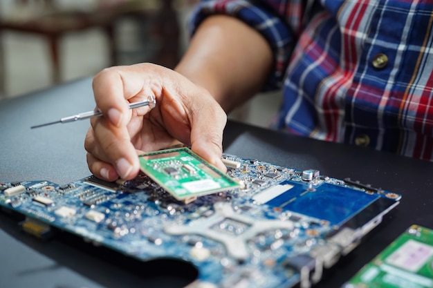 Asiatischer Techniker, der Mikroschaltungshauptbrettcomputer repariert.