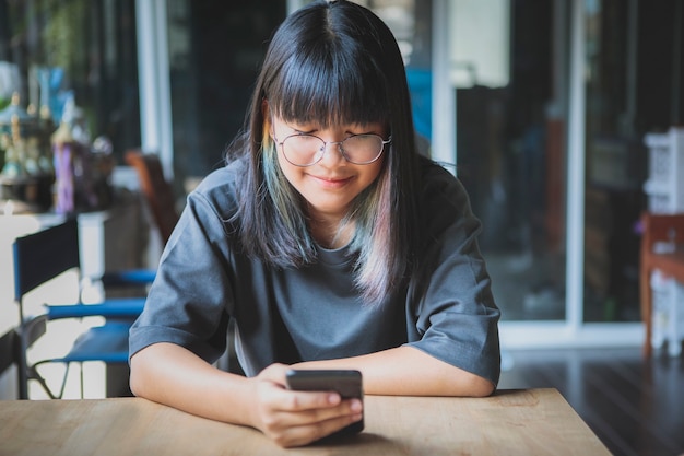 Asiatischer Teenager, der Nachricht auf Smartphone in der Hand liest