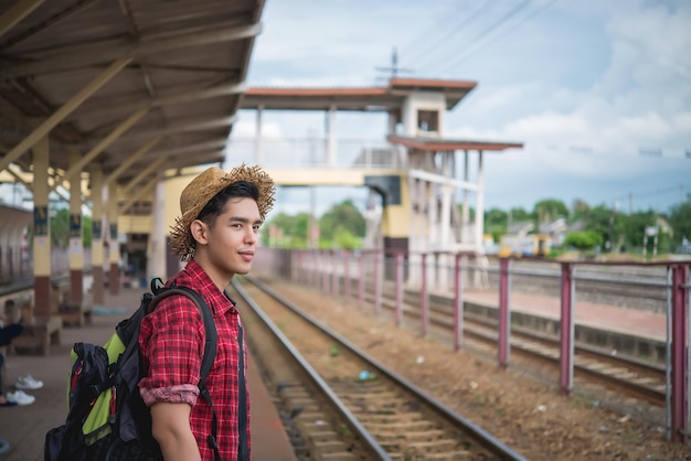 Asiatischer Touristenwartezug am Bahnhof Thailand-Hipster-Mann geht auf Reisen