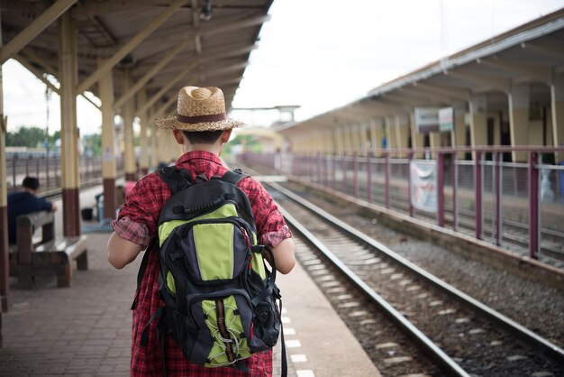 Asiatischer Touristenwartezug am Bahnhof Thailand-Hipster-Mann geht auf Reisen