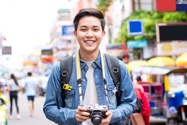 Asiatischer touristischer Fotograf, der in Bangkok, Thailand an den Feiertagen wandert