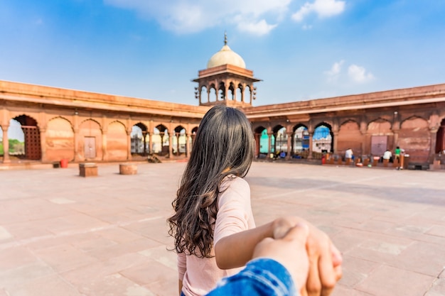 Asiatischer touristischer führender Mann der jungen Frau in die rote Jama Mosque in altem Delhi, Indien. Zusammen reisen. Folge mir.