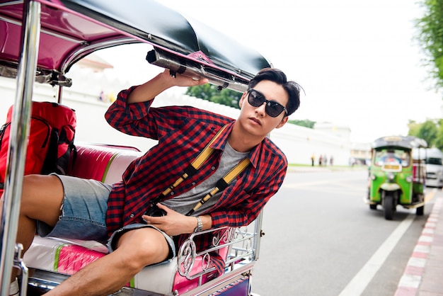 Asiatischer touristischer Mann, der TukTuk-Taxi beim Reisen in Bangkok Thailand reitet