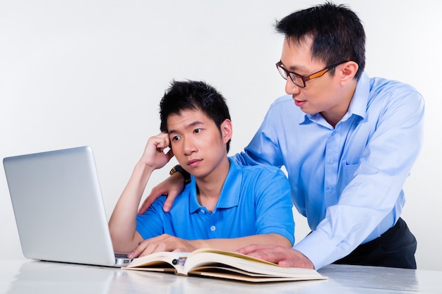 Asiatischer Vater und Sohn, die zu Hause für Schule lernt