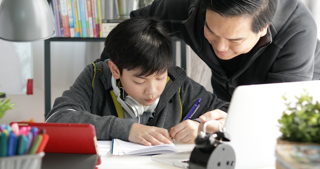 Asiatischer Vater und Sohn, die zu Hause Hausarbeit tut.