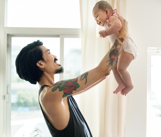 Asiatischer Vati, der sein Baby mit Liebe hochhält