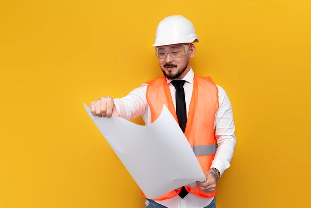 Asiatischer Vorarbeiter in Uniform mit Papieren und Projekten auf gelbem isolierten Hintergrund koreanischer Bauingenieur in Hardhat