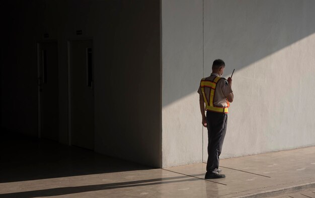 Asiatischer Wachmann mit Walkie-Talkie bei der Arbeit auf dem Bürgersteig in der Tiefgarage