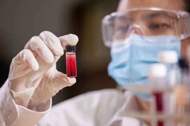 Asiatischer Wissenschaftler analysiert Blut im Reagenzglas und erforscht chemische Tests in einem Labor.