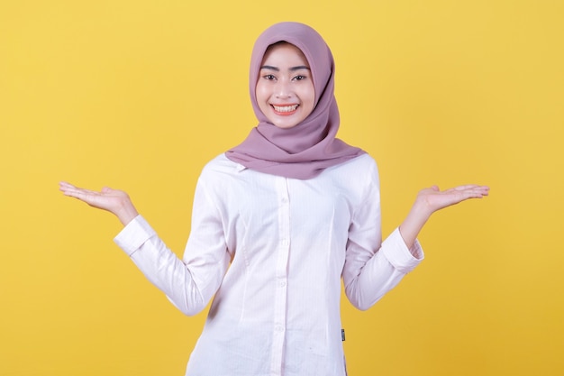 Asiatisches attraktives Mädchen, das etwas auf der Hand zeigt, das Hijab trägt