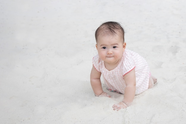 Asiatisches Baby, das auf dem Sand kriecht