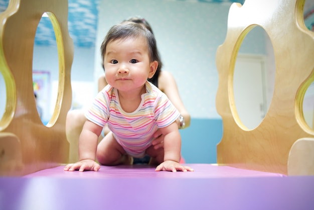 Asiatisches Baby genießen, im Kinderspielplatz zu spielen